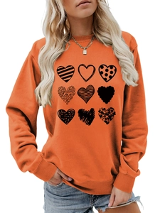 Detail of orange crewneck sweatshirt featuring nine artistic black heart patterns and LOVE text