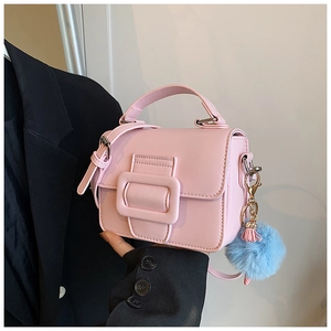 Dettaglio borsa a tracolla rosa con fibbia opaca e ciondolo pompon blu in peluche