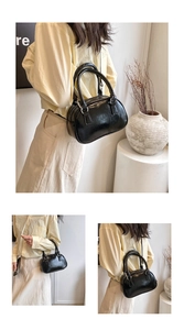 Detailed view of a black glossy bowling handbag with top handles and metallic zipper
