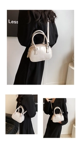 Detail of cream white patent leather bowling bag showing crossbody strap and top handles