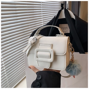 Dettaglio mini borsa squadrata bianca in pelle con fibbia e ciondolo di peluche