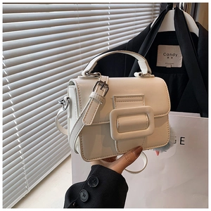 Dettaglio borsa a mano bianca con fibbia quadrata su sfondo di blazer nero e stile chic