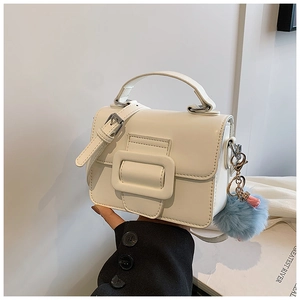 Dettaglio della mini borsa quadrata bianca con fibbia quadrata e ciondolo a pompon colorato