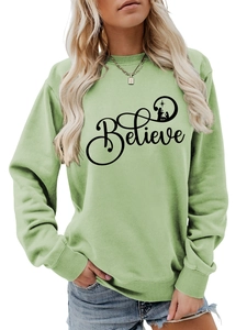 Detail of light green sweatshirt featuring black Believe text and nativity scene print