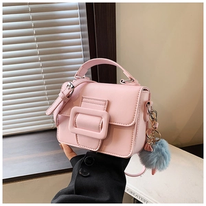Dettaglio mini borsa quadrata rosa chiaro con fibbia decorativa e ciondolo pompon blu