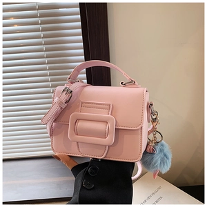 Dettaglio mini borsa quadrata rosa con finiture dorate e ciondolo pompon blu in pelliccia