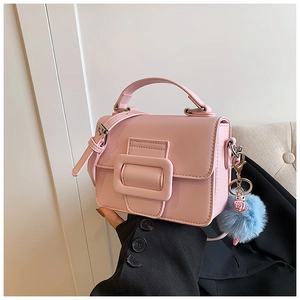 Borsa a mano quadrata rosa con grande fibbia e charm a pompon blu, mostrata da modella
