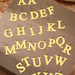 Detailed view of 26 alphabet letters gold earrings on textured brown display board