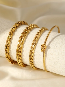 Detailed view of four assorted gold-tone link chains and a minimalist knot cuff bracelet
