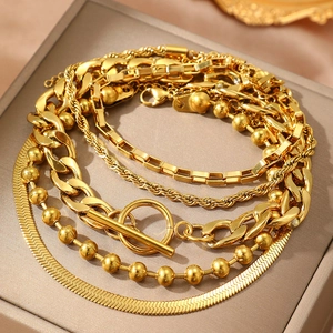 Detailed view of layered gold chain bracelet set with OT buckle and snake chain on jewelry box