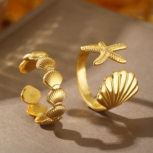Adjustable gold starfish and shell rings on grey silk background with ocean vibes