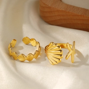 Detailed shot of golden sea shell and starfish adjustable rings on silk fabric
