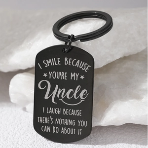 Engraved black stainless steel dog tag keychain for uncle on a white stone background