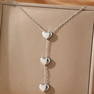 Minimalist stainless steel necklace featuring three heart pendants on a classic chain