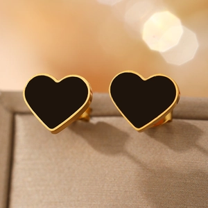 Elegant gold-plated stainless steel heart earrings with black onyx centers on a warm fabric