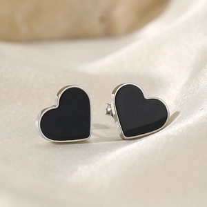 Elegant heart-shaped stainless steel earrings with black enamel on silk background