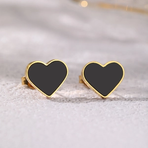 Macro shot of minimalist gold-plated heart earrings with black enamel inlay details
