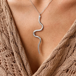 Gros plan d'un collier pendentif serpent en argent poli sur le cou d'une femme