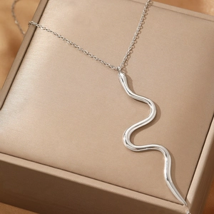 Collier avec pendentif serpent argenté sur une boîte à bijoux en satin de couleur champagne