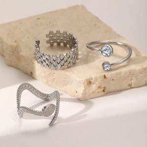 Three-piece silver titanium steel ring set with hollow heart and zircon on stone surface