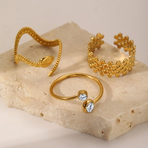 Detailed shot of three gold plated titanium rings with woven mesh and zircon on stone