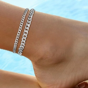 Détail de bracelets de cheville argentés à double couche à mailles gourmettes à la mer