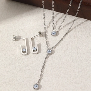 Elegant stainless steel jewelry set featuring diamond-encrusted necklaces and J-shaped earrings