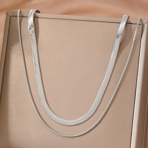 Double-layer silver snake bone necklace set in stainless steel displayed on a stand