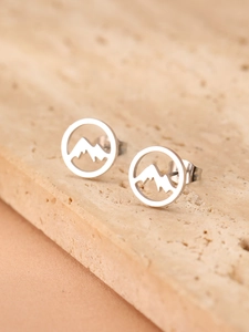 Close-up of stainless steel mountain silhouette stud earrings on a textured stone