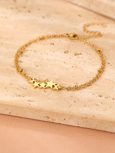 Detail eines goldenen zweischichtigen Sternanhänger-Armbands mit Perlen und Verschluss
