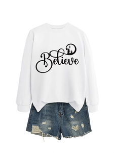 Flat lay of a white crewneck sweatshirt with Believe print and frayed blue denim shorts