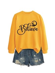 Close-up of yellow sweatshirt featuring Believe text and nativity silhouette design