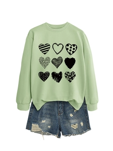 Detail view of light green crewneck sweatshirt featuring nine heart patterns and side slit hem