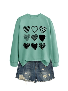 Flat lay of mint green sweatshirt with nine heart patterns and distressed denim shorts