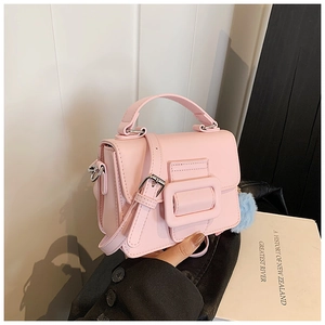 Dettaglio della mini borsa quadrata rosa chiaro con grande fibbia e pompon blu