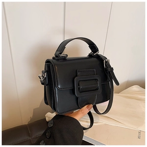 Dettaglio di una mini borsa a tracolla nera con grande fibbia e finiture in argento