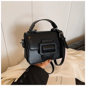 Dettaglio mini borsa in pelle nera opaca con fibbia quadrata e pompon rosa soffice