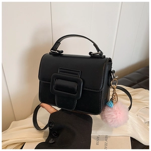 Dettaglio di una mini borsa quadrata nera opaca con fibbia abbinata e ciondolo rosa