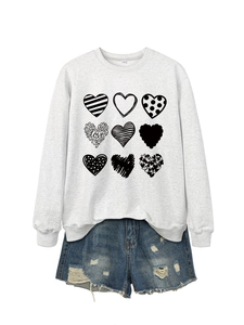 Detail of white crewneck sweatshirt with nine heart prints and distressed denim shorts