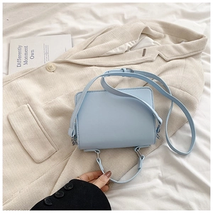 Dettaglio mini borsa a mano quadrata celeste su tessuto bianco con finiture argento