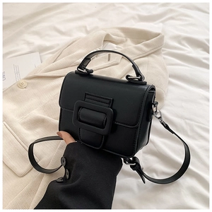 Dettaglio di una borsa quadrata vintage nera con grande fibbia d'argento su lino bianco