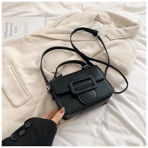 Dettaglio della mini borsa quadrata nera in pelle sintetica con manico e fibbia decorativa