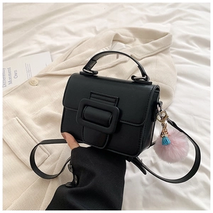 Dettaglio della mini borsa quadrata nera con maxi fibbia, pompon rosa e nappa blu scuro