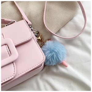 Dettaglio borsa quadrata in ecopelle rosa con fibbia e ciondolo pompon blu peluche