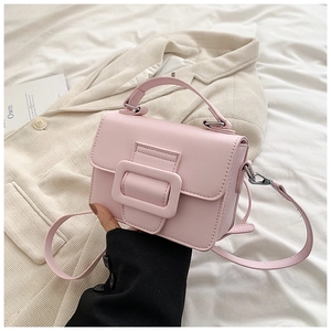 Dettaglio mini borsa quadrata rosa chiaro con grande fibbia decorativa su un blazer crema