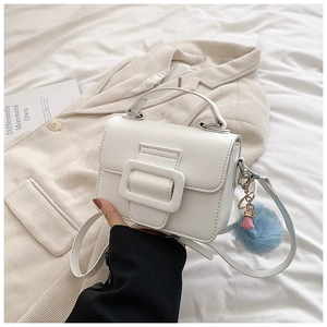 Dettaglio della mini borsa quadrata bianca in pelle opaca con ciondolo a pompon blu