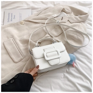 Dettaglio della mini borsa bianca con fibbia decorativa e ciondolo a pompon blu