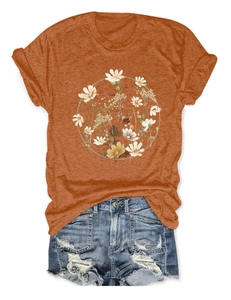 Flat lay of a mustard yellow floral wreath t-shirt and distressed denim shorts outfit