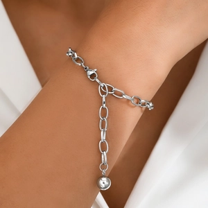 Close-up of a silver stainless steel link bracelet with orb pendant on a woman's wrist