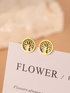 Close-up of golden Tree of Life earrings with intricate laser-cut detail on a pink card